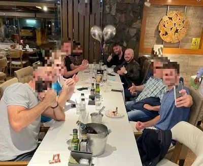 A long dinner table in South America with Dylan and a group of business owners, faces blurred for privacy