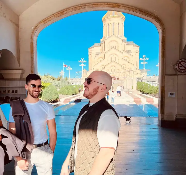 Dylan laughing with friends visiting from Germany and Canada, under an archway at Holy Trinity Cathedral in Tbilisi